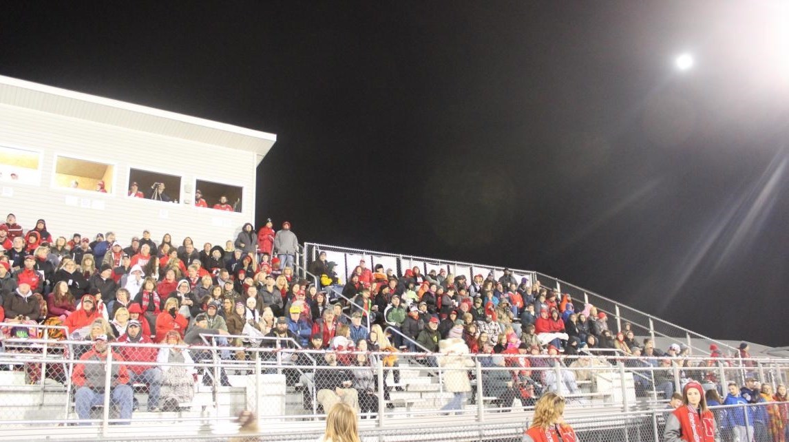 Large crowd of people sitting on bleachers at night