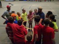 Students and teachers gathered around a yellow hoop in a gymnasium
