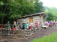 Students learning how to use a long saw on a log