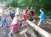 Students learning how to use a long saw on a log